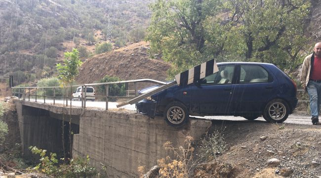 Kayganlaşan yolda kaza yapan otomobil köprüde asılı kaldı